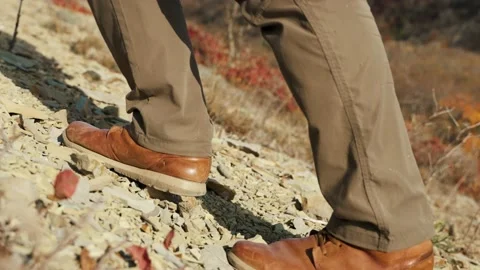 Men foot steps in the mountains. A close-up on the traveler brown boots. Stockbeeldmateriaal 224468921