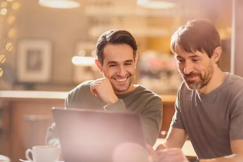 Men friends using laptop and drinking coffee in cafe Stock Photos