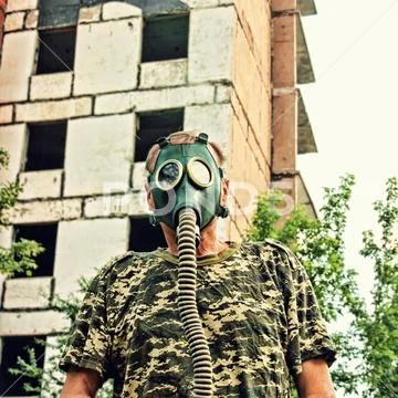 Men in gas mask looks at camera against the ruined building. Apocalyptic conc Stock Photos