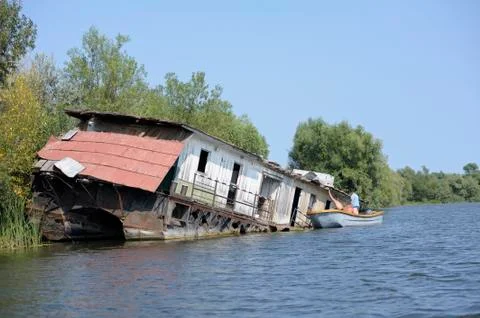 Men getting inside of the abandoned ship, motorboat moored Stock Photos