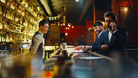 Men greeting bar worker ordering drinks at evening. Cheerful customers enjoying Stock Footage 319797826