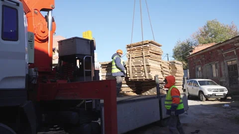 Men guide dangling concrete stack with rope-bound control Stock Footage 314649086