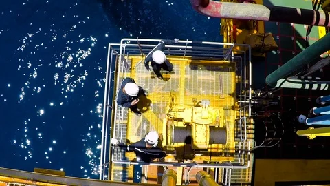 Men hammering stuck winch operation of life boat offshore Stock Footage 89166864