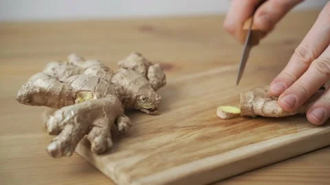 Men hands cut with a knife ginger root on wooden cutting board Video stock 149909472