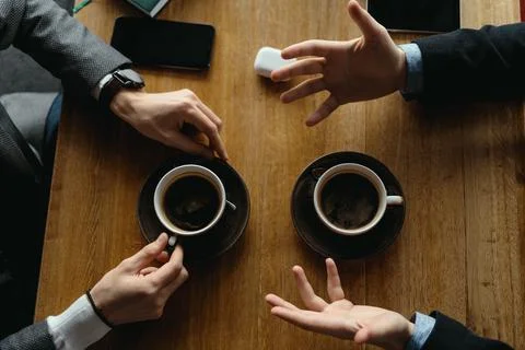 Men hands gesticulating while holding cups of coffee Stock Photos