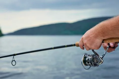 Men hands kept spinning on the background on the evening river Stock Photos