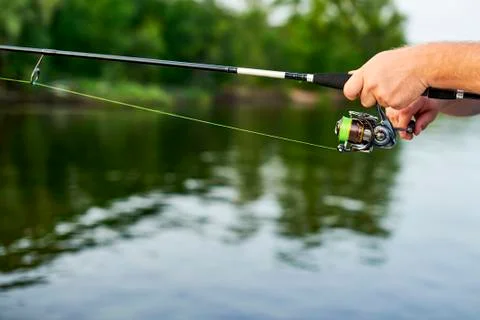 Men hands kept spinning on the background of the river Stock Photos