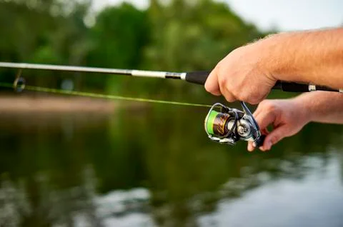 Men hands kept spinning on the background of the river Stock Photos