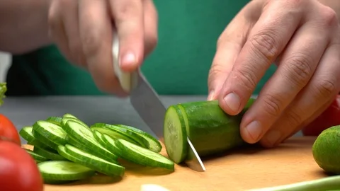 Men hands with knife cutting green cucumber for salad Video stock 109797793