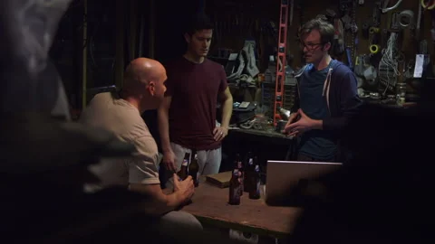 Men having beers while talking with each other in a garage Stock Footage 202907841