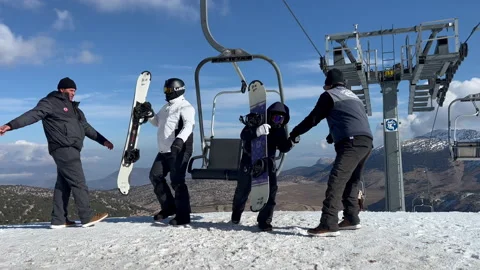 Men help snowboarders to get out of the chairlift in davraz mountains in ant Stock Footage 231136400