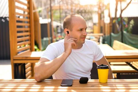 Men includes finger at wireless ear bud earphones inside ear. Stock Photos