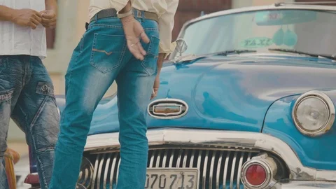 Men in jeans stand in front of classic cuban car on street in havana Stock Footage 88763323