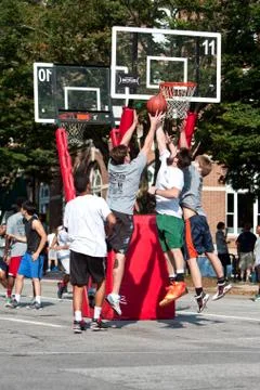 Men jump while fighting for ball in street basketball tournament Stock Photos