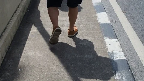 Men leg walking on bridge sidewalk under bright sunlight with shadow Stock Footage 82331644