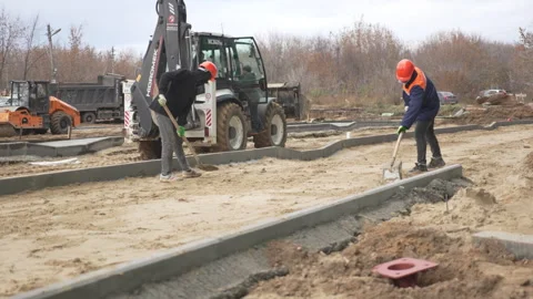 Men level soil in trenches while bulldozer compacts sand Stock-Footage 306417938