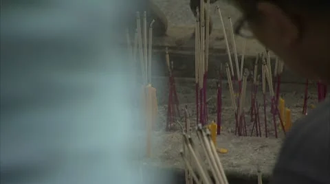 Men lighting row of candles and incense sticks at shrine, Bangkok Stock-Footage 12761673