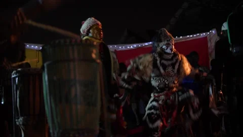 Men in lion costume dancing on beach with crowd around Stock Footage 208940939