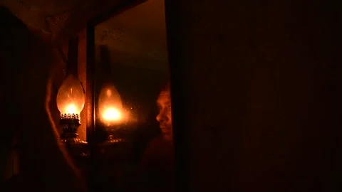 Men looks in an old mirror under the light of a kerosene lamp Stock Footage 135380397