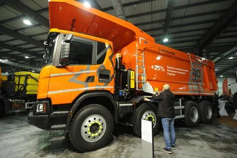 Men measuring parameters of a new model of a dump truck Scania parked on a st Stock Photos
