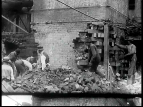 Men pickax and shovel bricks into a pile, dismantling and prepping an old 動画素材 75754414