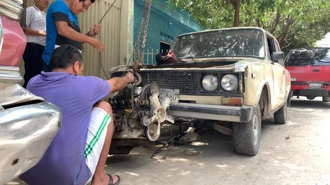Men place car engine on ground with a chain Stock Footage 109521209