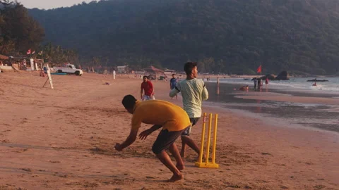Men play cricket on beach Stock Footage 142212115