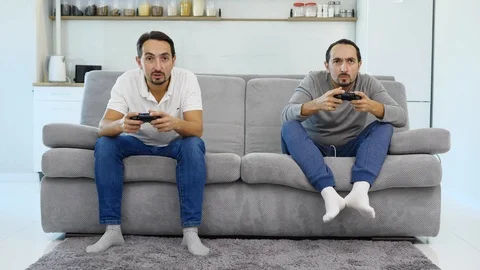 Men play the game while sitting on the couch  Stock Footage 99846289