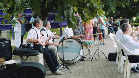 Men play musical instruments in the orchestra in the park on summer day 動画素材 76891862