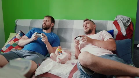Men play video games while babysitting Video stock 138649935