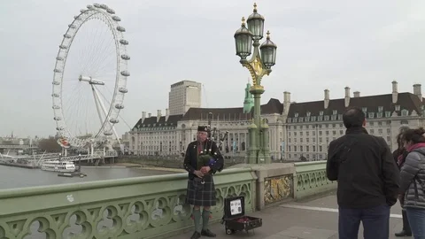 Men playing on a bagpipe dressed on Westminster Bridge in London Stock Footage 82967934