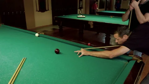 Men playing billiards, hitting balls with cue into pockets on billiard table. 4K Stock Footage 109411373
