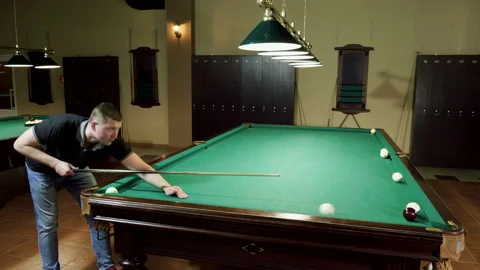 Men playing billiards, hitting balls with cue into pockets on billiard table. 4K Stock-Footage 109452734