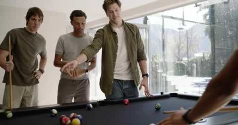 Men playing at pool table at home watching gesturing, shooter hitting cue ball, Stock Footage 339959822