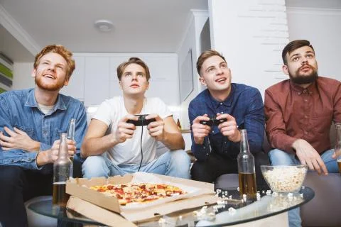 Men playing soccer on game console together at home Stock Photos