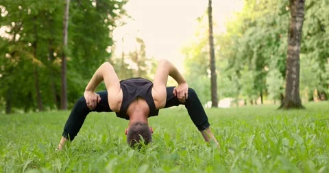 Men practicing yoga and meditating in park at sunny summer day. Young man doing Video stock 156981450