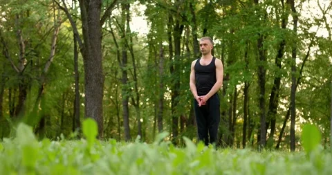 Men practicing yoga and meditating in park at sunny summer day. Slow motion Stock Footage 157736779