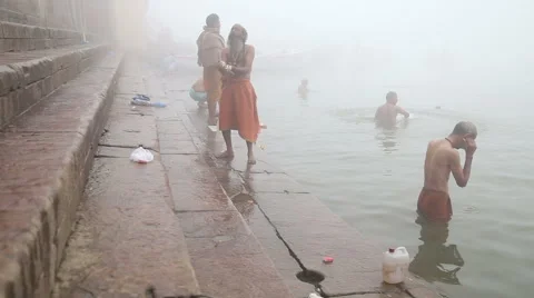 Men praying and bathing on shore of foggy Ganges river in Varanasi. Stock Footage 50351619