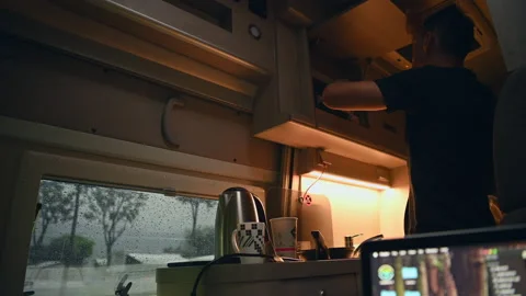 Men Preparing Hot Tea Inside His RV Camper Van During Rainy Day Video stock 141039675