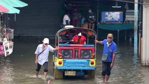 Men pull a Tuk Tuk motor tricycle stuck in a flooded street Stock Footage 234461275