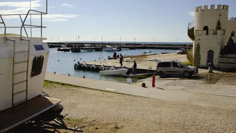 Men pulling a boat onto a car trailer in the seaport Stock Footage 214331264