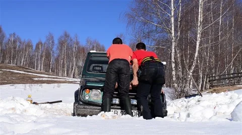 Men pushing a car trying to get her out of snow Stock Footage 61919396
