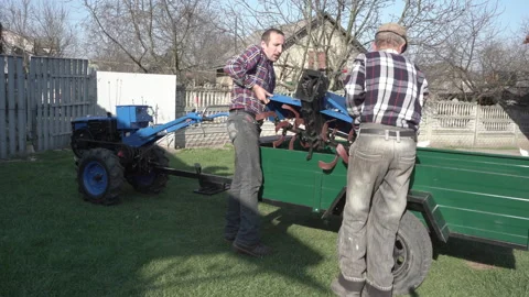 The men put the cutter for the walk-behind tractor in the trailer Stock Footage 247786190
