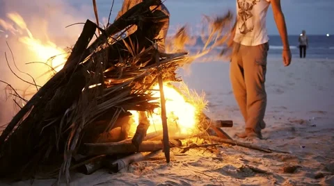 Men put a log on the big fire on beach party. Slow motion. Stock Footage 56067226
