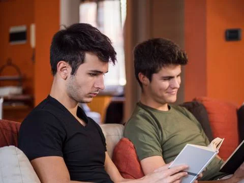 Men reading textbooks on sofa Stock Photos