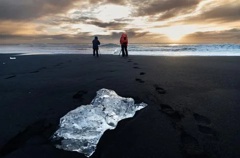 Men in red and black jacket photographed ice blocks on diamond beach Stock Photos