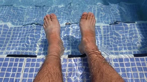 Men refreshing and swinging his legs in the swimming pool Stock Footage 138327268
