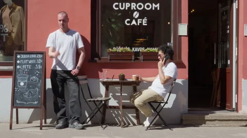 Men Relaxing and Drinking Coffee Outside a Cafe in Vilnius Stock Footage 334771780