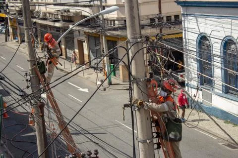 Men repairing electrical grid wires using masks because of COVID-19 Foto stock