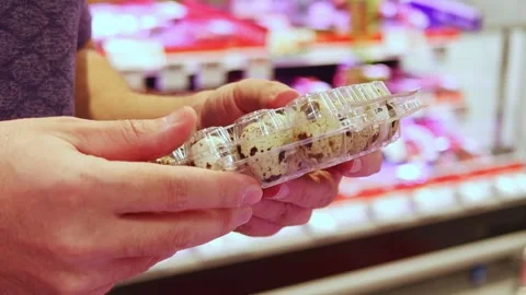 Men selecting trays of fresh quail and chicken eggs at a grocery store Stock Footage 324874167